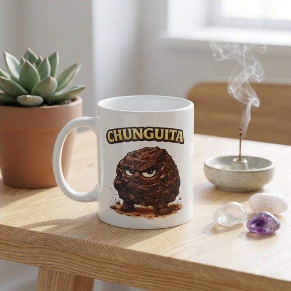 Taza de cerámica con ilustración de personaje Chunguita piedra shungit con cara enfadada sobre mesa de madera minimalista